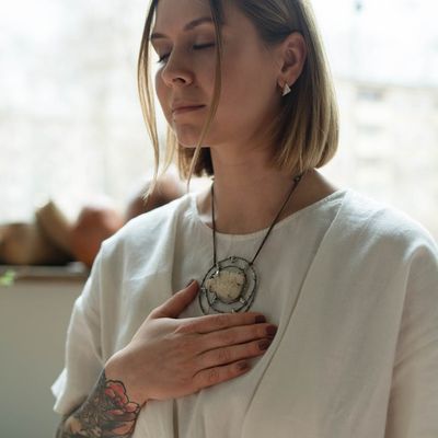 Person taking a moment to breathe with eyes closed in a calm setting.